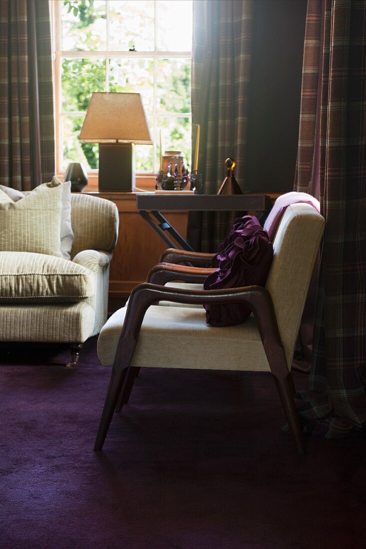 Traditionelle Wohnzimmerecke mit hellen Sesseln im Fiftiesstil und Art Deko Tischleuchte im Fenster