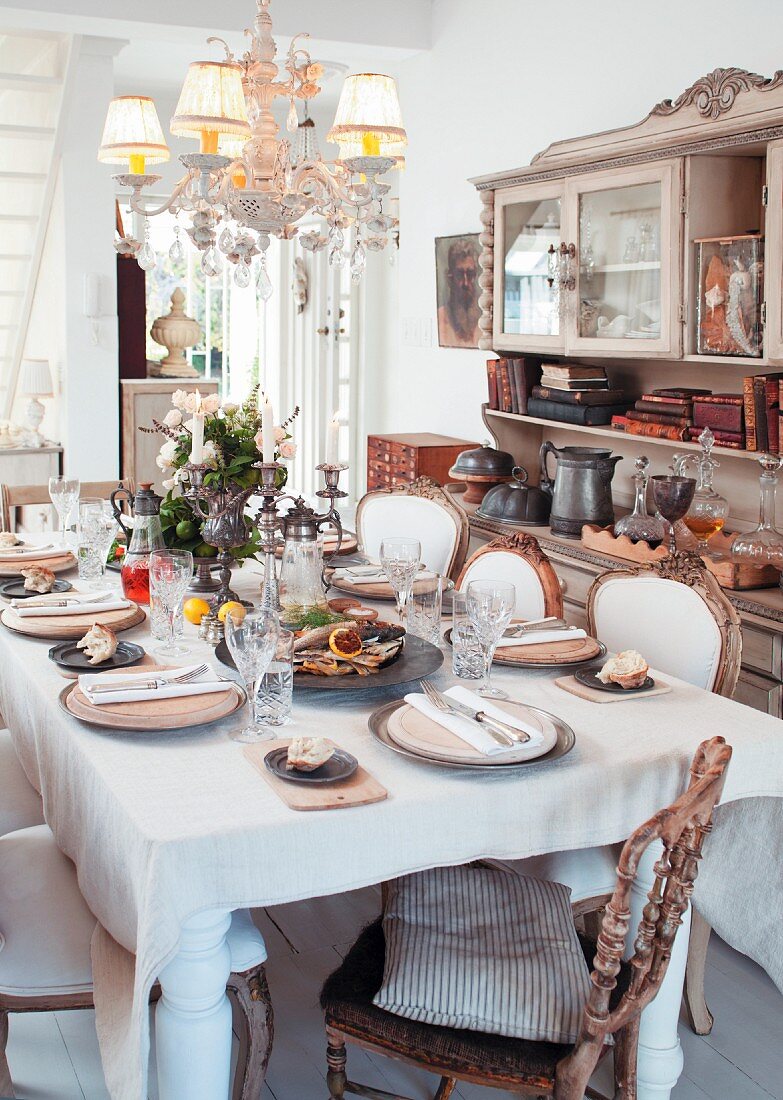 Gedeckter Tisch in Wohnraum mit antike Stühlen & Buffetschrank