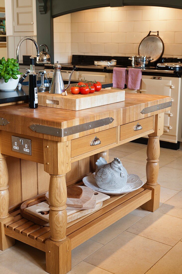 Tomatoes and vinegar jug on chopping block with solid wooden frame in front of vintage cooker in niche