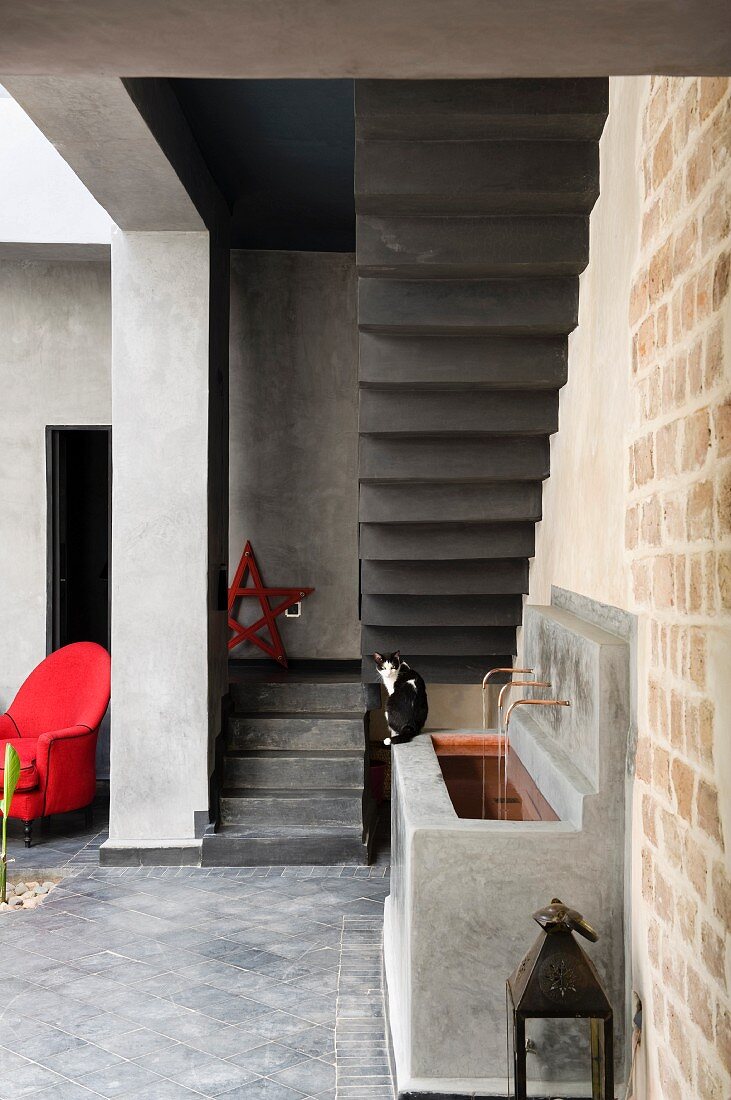 Sink and red armchair in courtyard of Marrakesh home