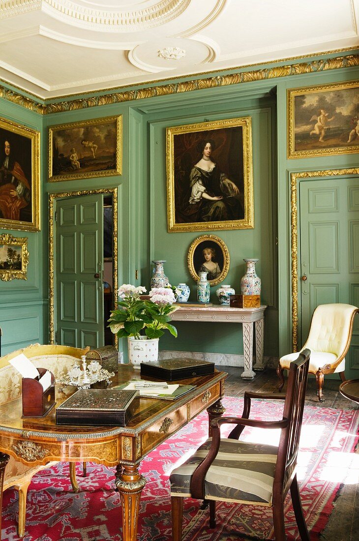 Baroque writing room with upholstered furniture and gilt-framed oil paintings on green walls