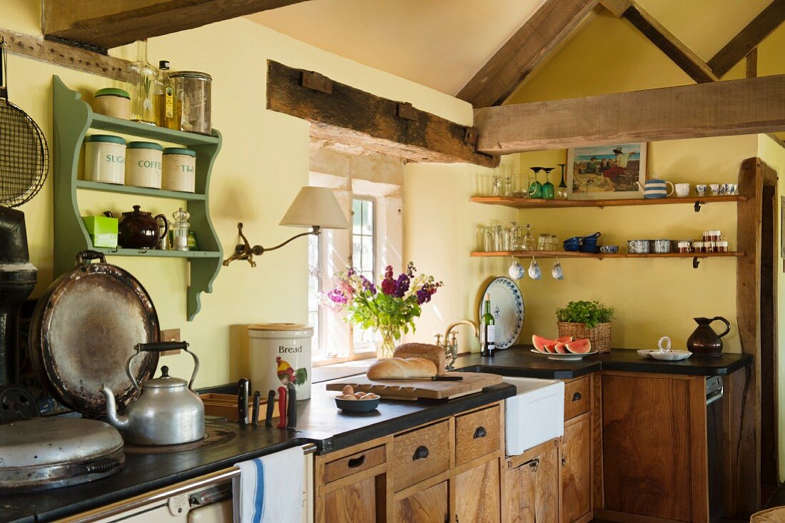 Rustikale Küchenecke eines englischen Landhauses mit sichtbarer Fachwerkkonstruktion, antikem Herd und bestückten Küchengeschirrboards