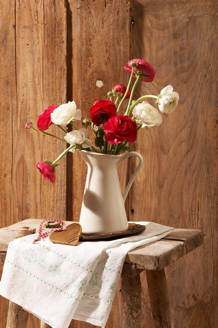 Red and white ranunculus in a pitcher