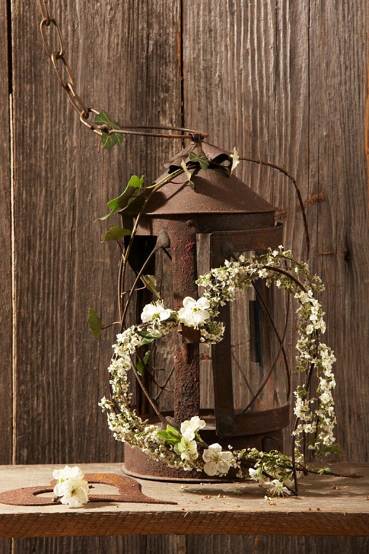Heart-shaped wreath with white flowers by a rusty lantern