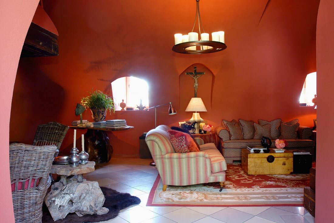Red-painted living room in Romanesque house with sofa combination below wrought iron pendant lamp