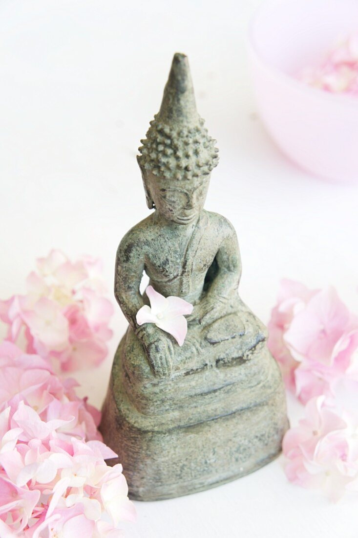 Buddhastatue und rosa Blütenblätter