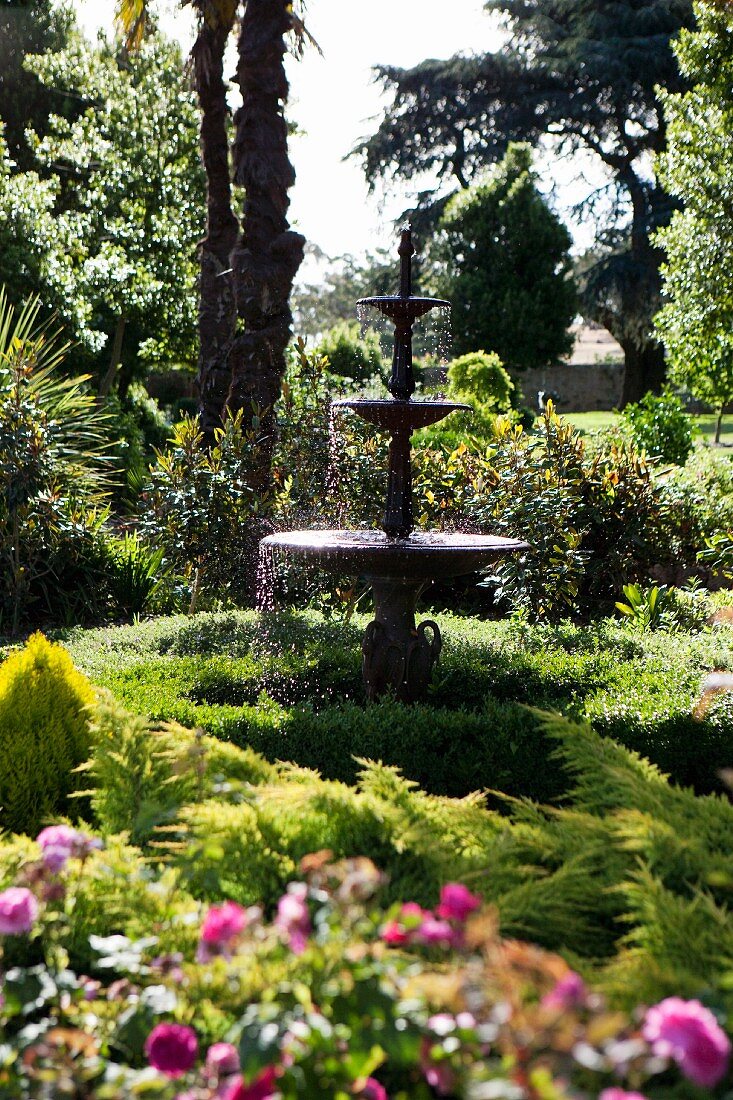 Classical, multi-level fountain between the magnificent green of a historic garden