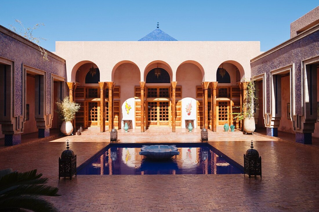 Wasserbecken in gefliestem Innenhof vor moderner, marokkanischer Villa