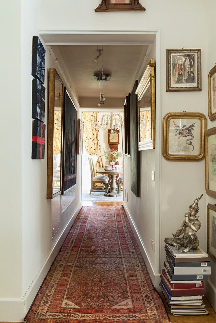 Hallway with view into tasteful villa dining room; large collection of artworks decorating the walls