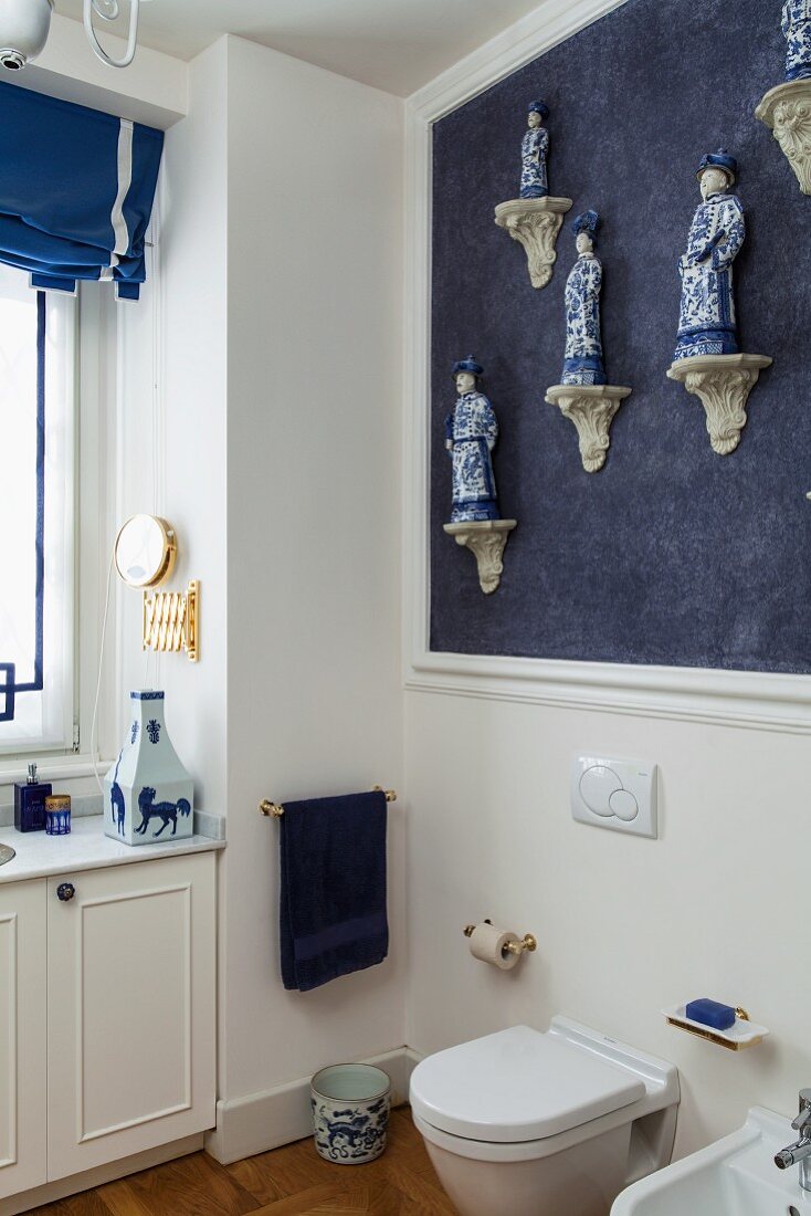 Helle Badezimmerecke mit einer Sammlung chinesischer Porzellanfiguren an blauer Wand