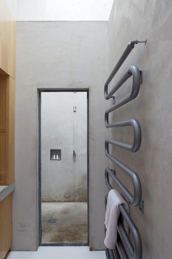 Zeitgenössischer Handtuchhalter an der Rohbetonwand eines minimalistischen Badezimmers