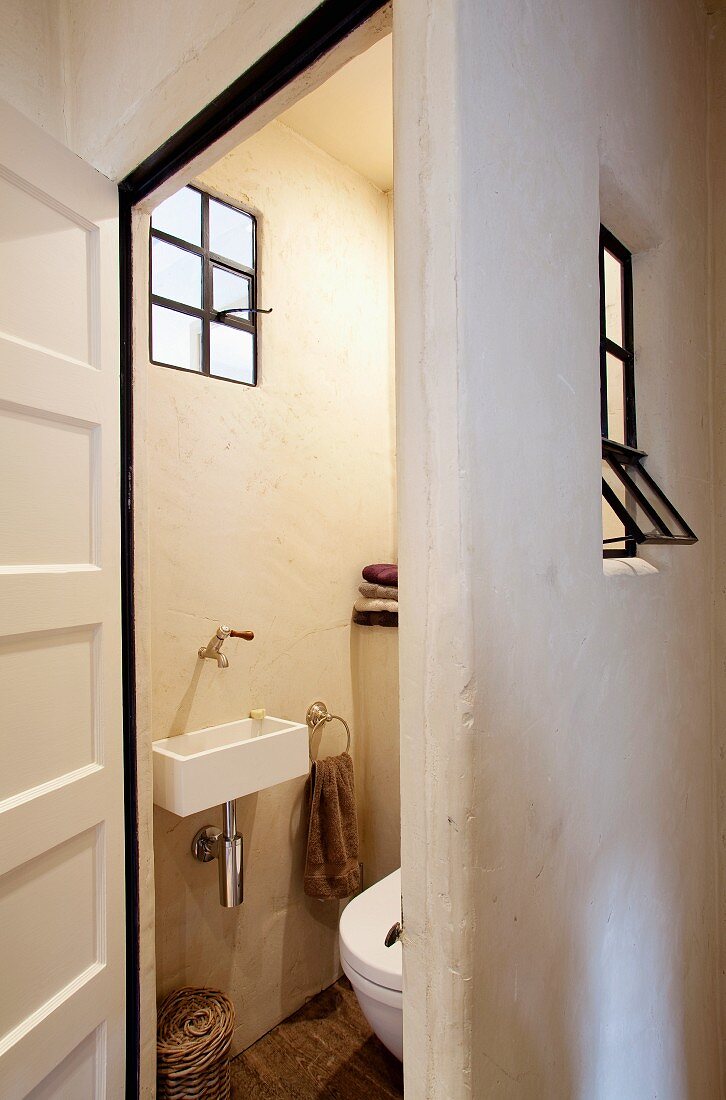 Blick in ein Gäste-WC mit alten Eisenfenstern und traditioneller Kalksteinwand