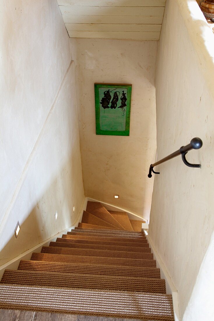 Blick vom Treppenabsatz nach unten auf eine gewendelte Treppe mit Sisalstufen