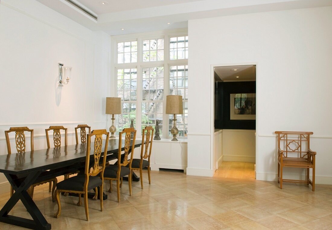 Antike Stühle und Esstisch in elegantem Esszimmer mit hellem Mosaikparkett und hoher Sprossenfensterfront