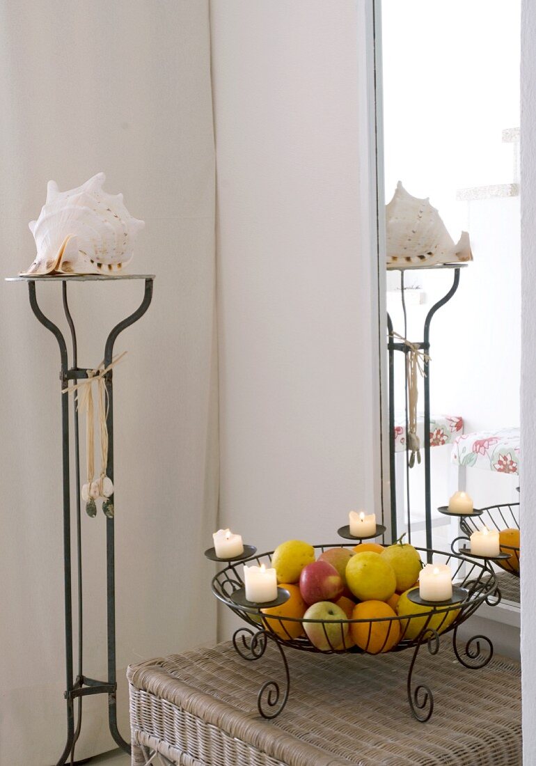 Helle Zimmerecke mit großem Spiegel und Korbtisch; darauf ein Kerzenhalter der auch als Obstkorb dient