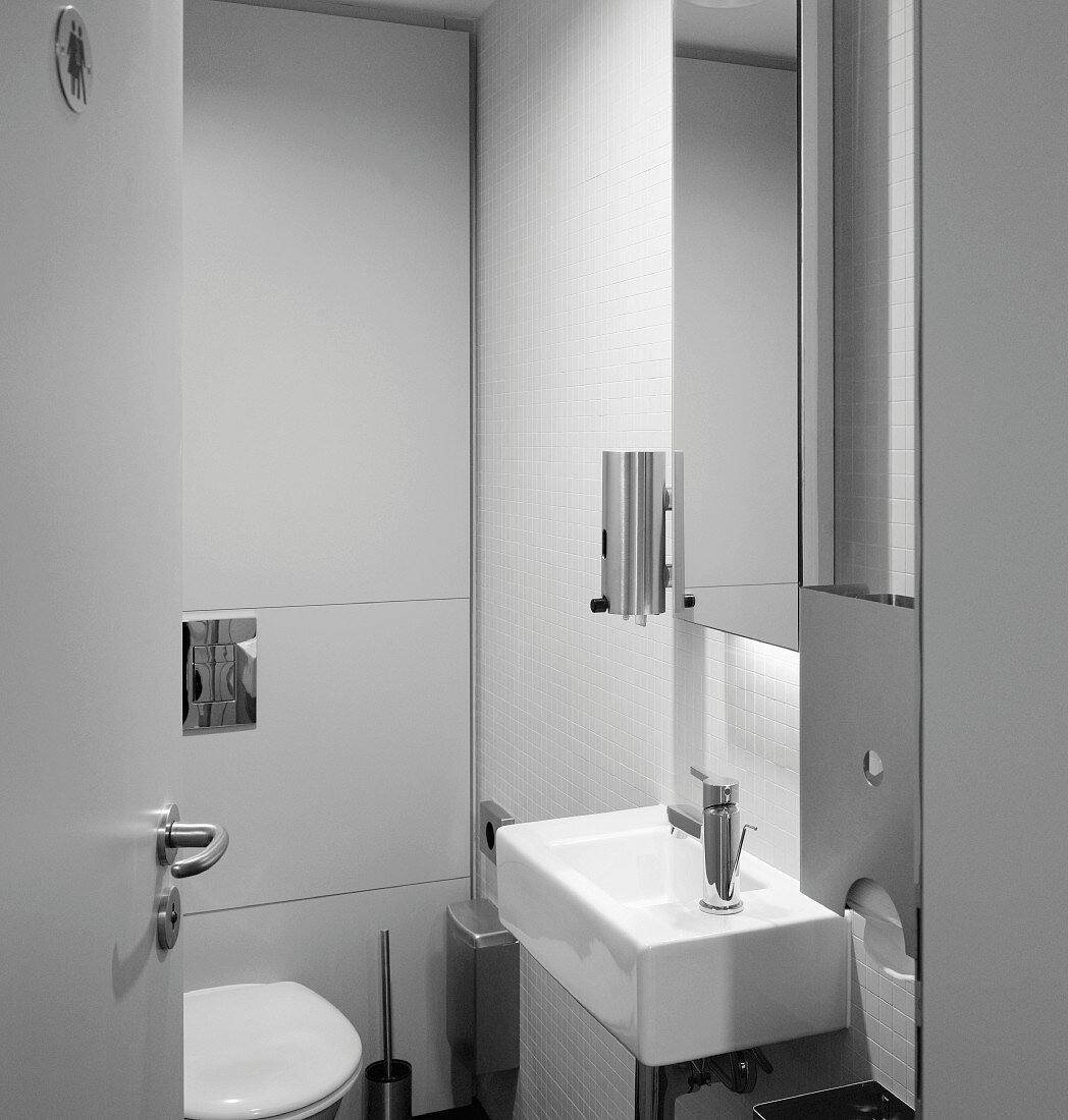 View through an open door of a vanity sink with mirrored medicine cabinet in a modern bathroom (Goethe Institut, London)
