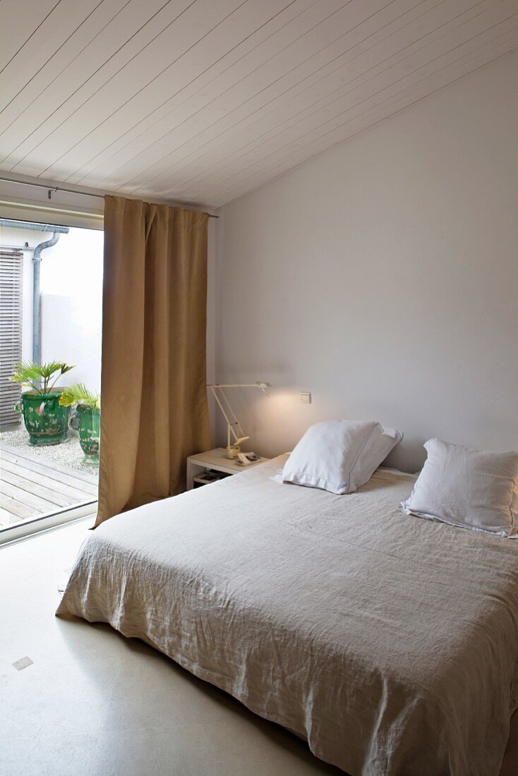 Schlichtes Schlafzimmer mit Doppelbett an raumhohem Fenster