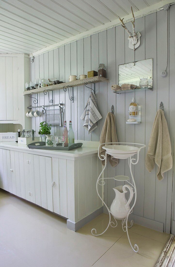 Skandinavische weiße Küchenecke mit nostalgischem filigranem Waschtischmöbel, Waschkrug und Waschschüssel darüber ein Wandspiegel