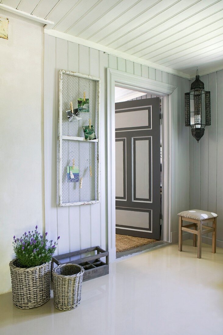 Flurbereich eines skandinavischen Holzhauses mit umfunktioniertem Fensterflügel als Pinwand und geöffneter bemalter Zimmertür