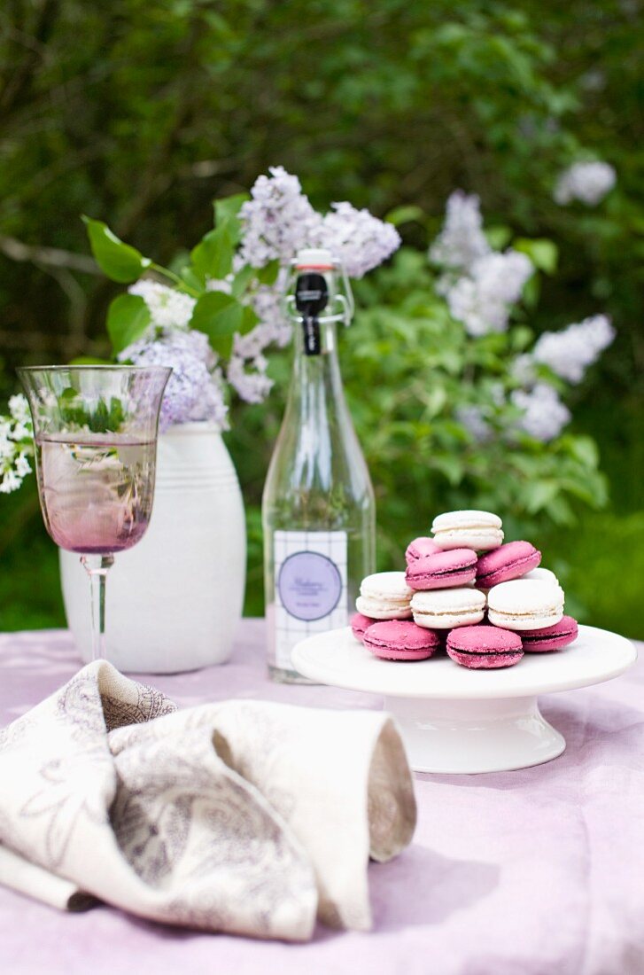 Garden table with lilac linen tablecloth and pink and white macaroons on white cake stand
