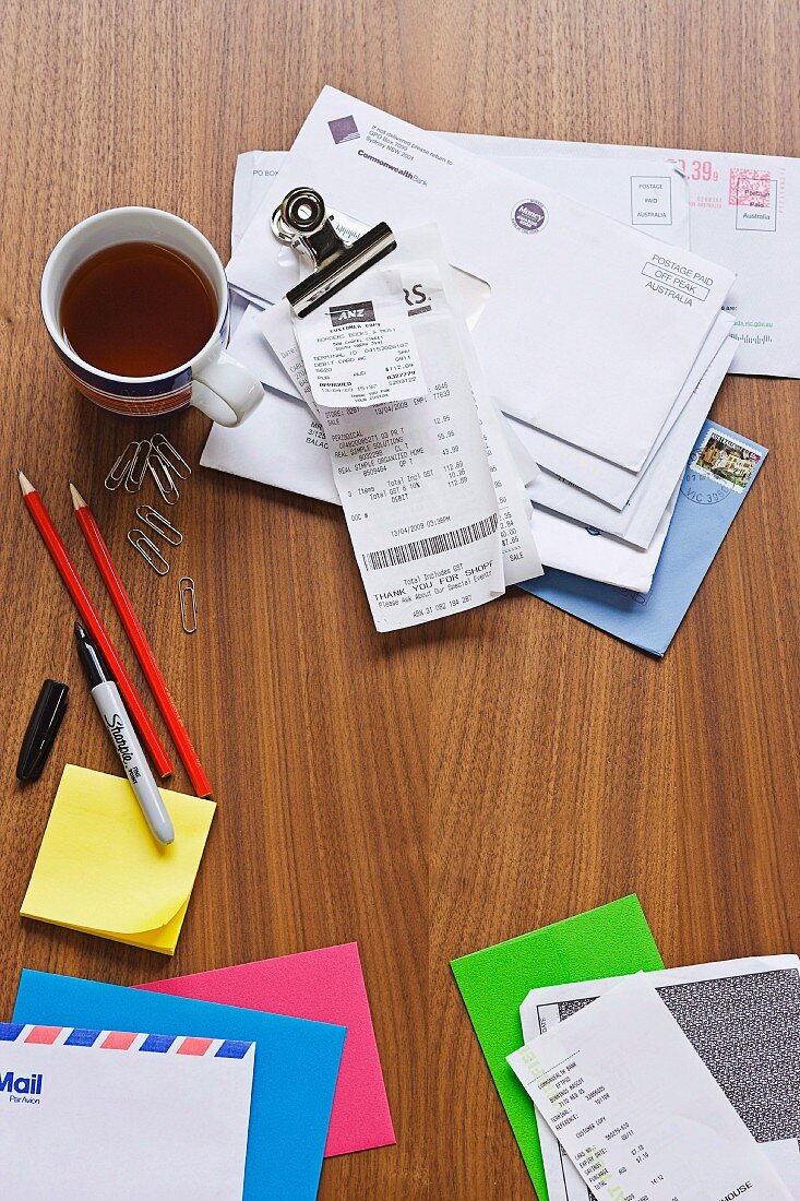 Writing utensils, letters and teacup on desk