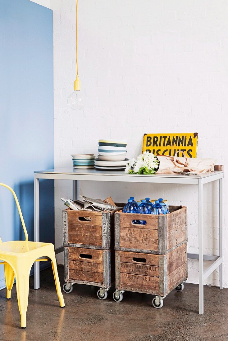 Old wooden crates on castors under simple console table in kitchen