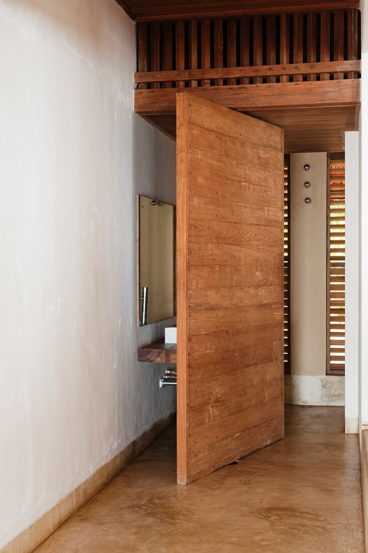 Trennwand aus Massivholz; dahinter ein hölzerner Waschtisch und ein Wandspiegel