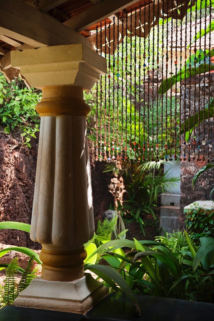 Vordach auf mächtiger Säule im Kolonialstil in tropischem Garten