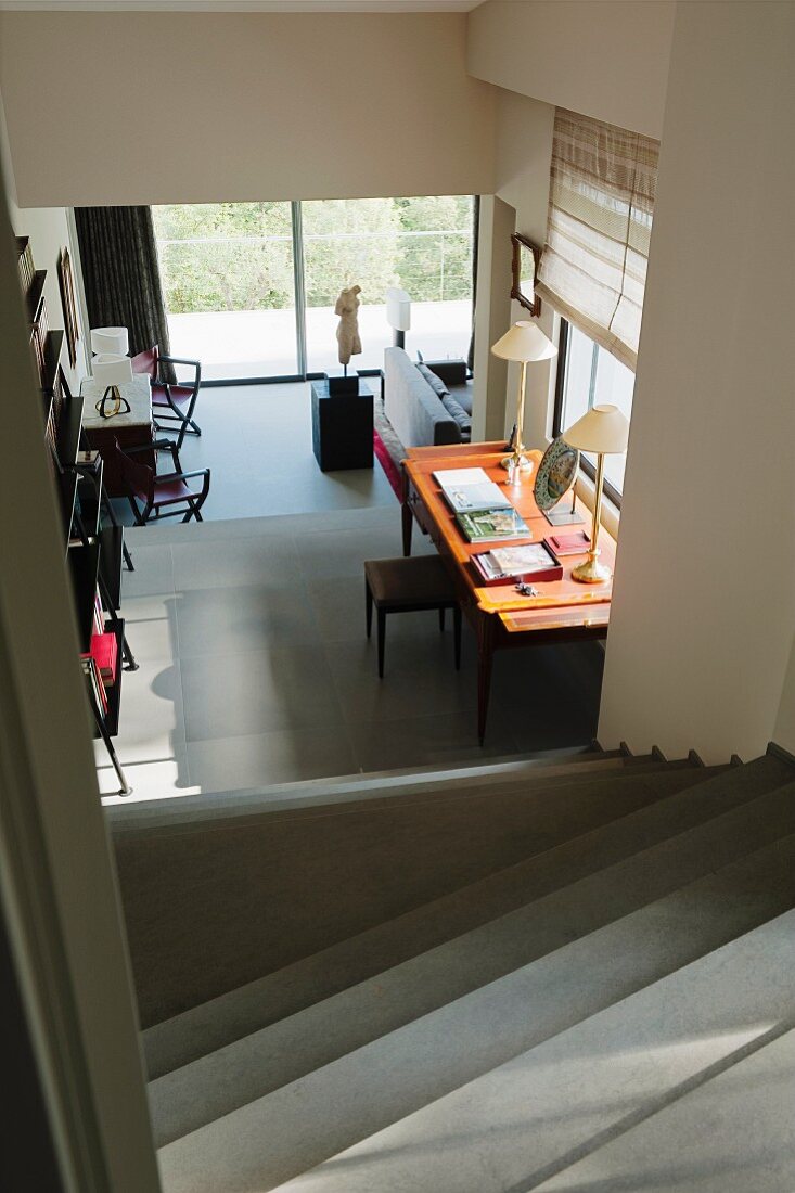 View down staircase into open-plan interior with workstation below window