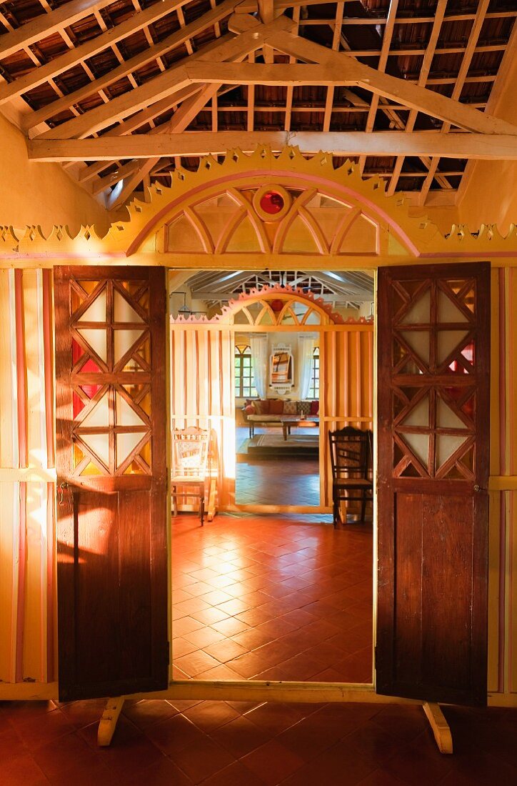 Blick durch offene Türen in Holztrennwand mit Schnitzereien im Rundbogen in traditionellem Wohnhaus
