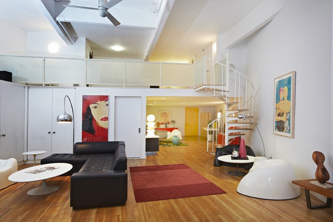Loftcharakter im zweigeschossigen Wohnraum mit Designer-Retromöbeln und einer Wendeltreppe auf die offene Galerie