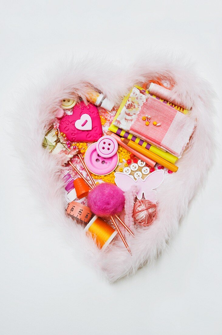 Assorted sewing and craft supplies in a heart shape