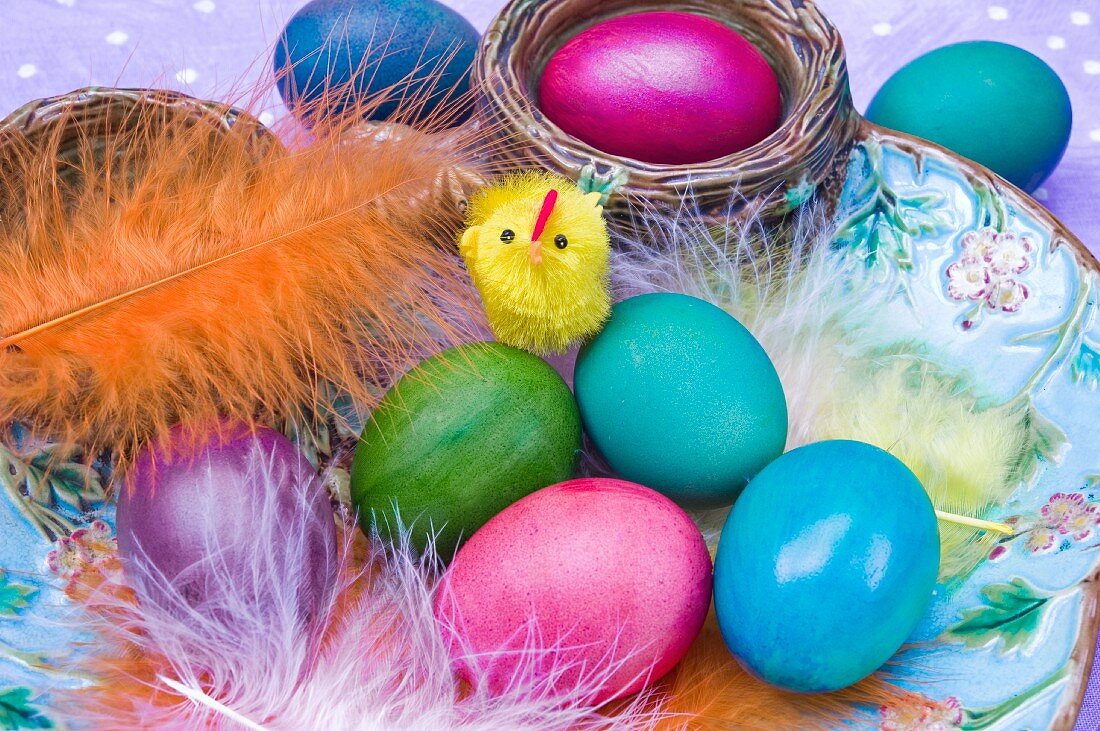Easter eggs and feathers in a ceramic bowl