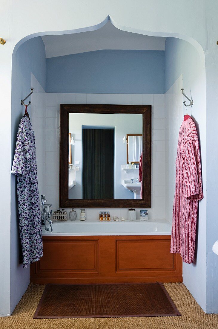 Large mirror above a bath set into an alcove with an oriental arch.