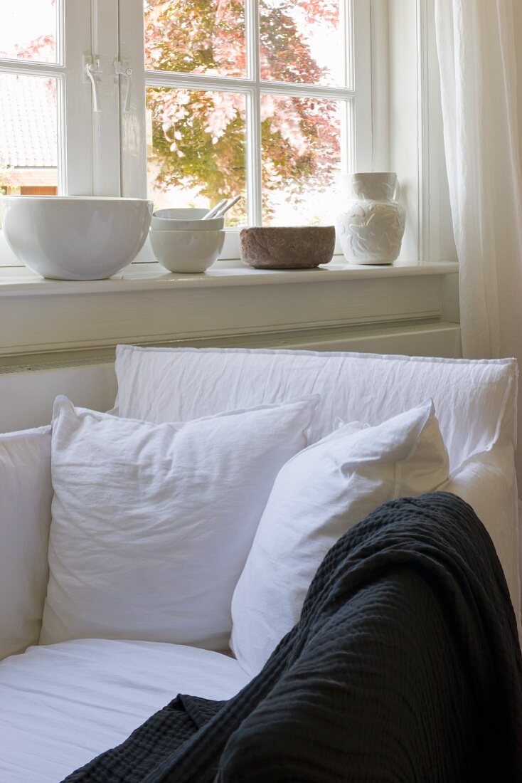 Gemütlicher Fensterplatz mit weißem Polstersessel und Kissen