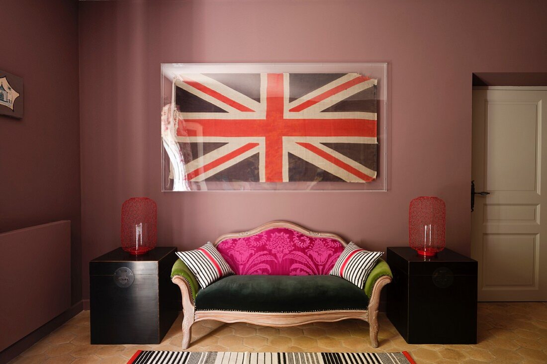 Union Jack Flagge hinter Glas über schrill gestaltetem Antiksofa in braunrosa getöntem Wohnraum