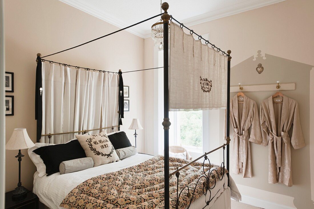 Iron four-poster bed adorned with vintage linen by Starched and Crumpled