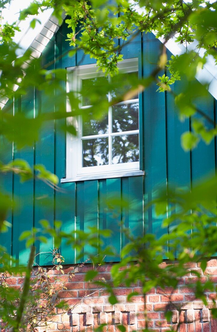 Blick auf Klinkerhaus mit petrolfarbenem Holzgiebel