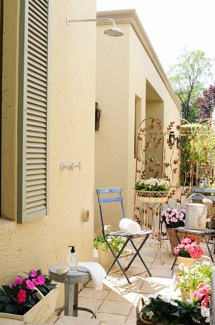 Aussendusche an Hauswand auf Terrasse romatisch dekoriert mit Blumentöpfen & Accessoires