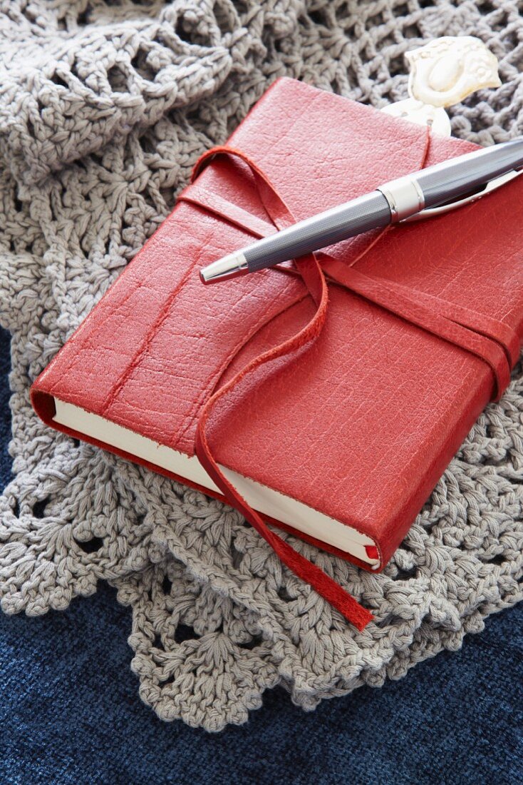 Kleines Buch mit Ledereinband auf gehäkelter Decke