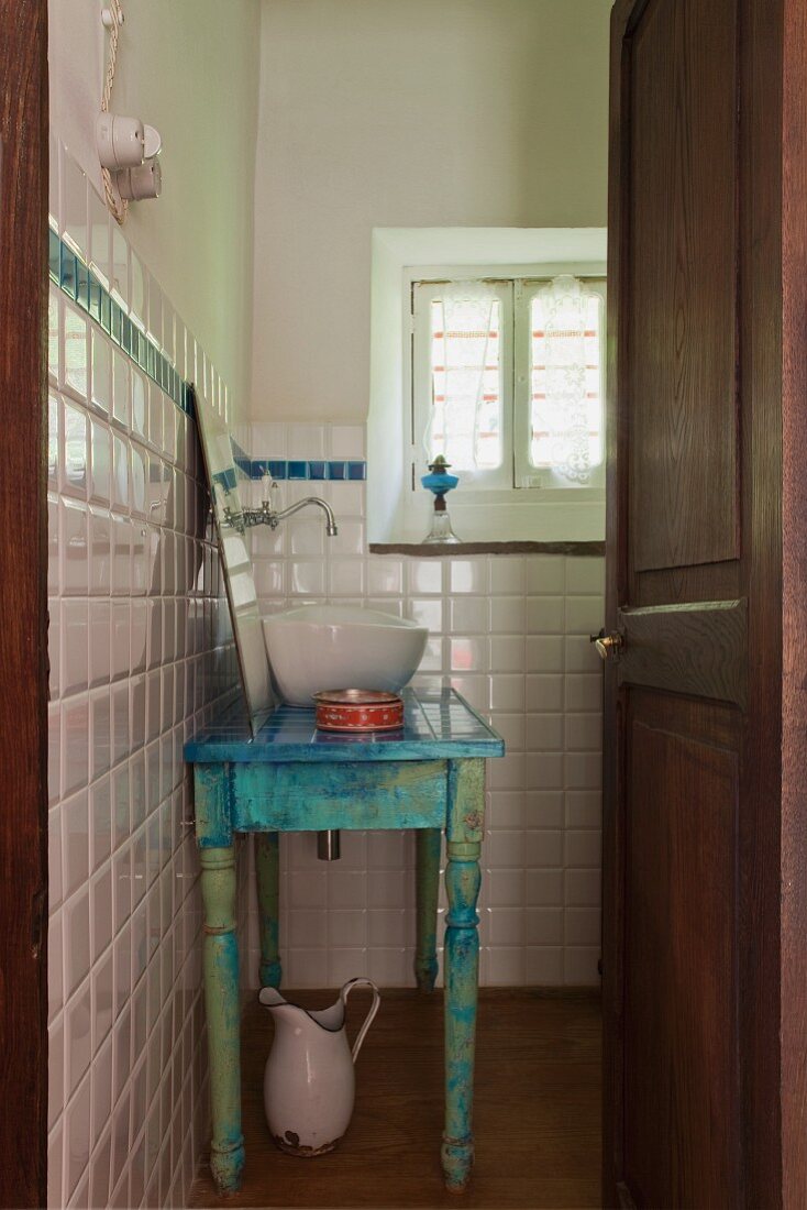 Badezimmer mit Waschtisch im Shabby Stil, angelehntem Badezimmerspiegel und einer modernen Waschschüssel aus Porzellan