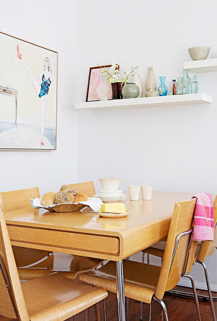 Essbereich mit Möbeln aus hellem Brettschichtholz und Wandbord mit gesammelten Glasflaschen in der Küche