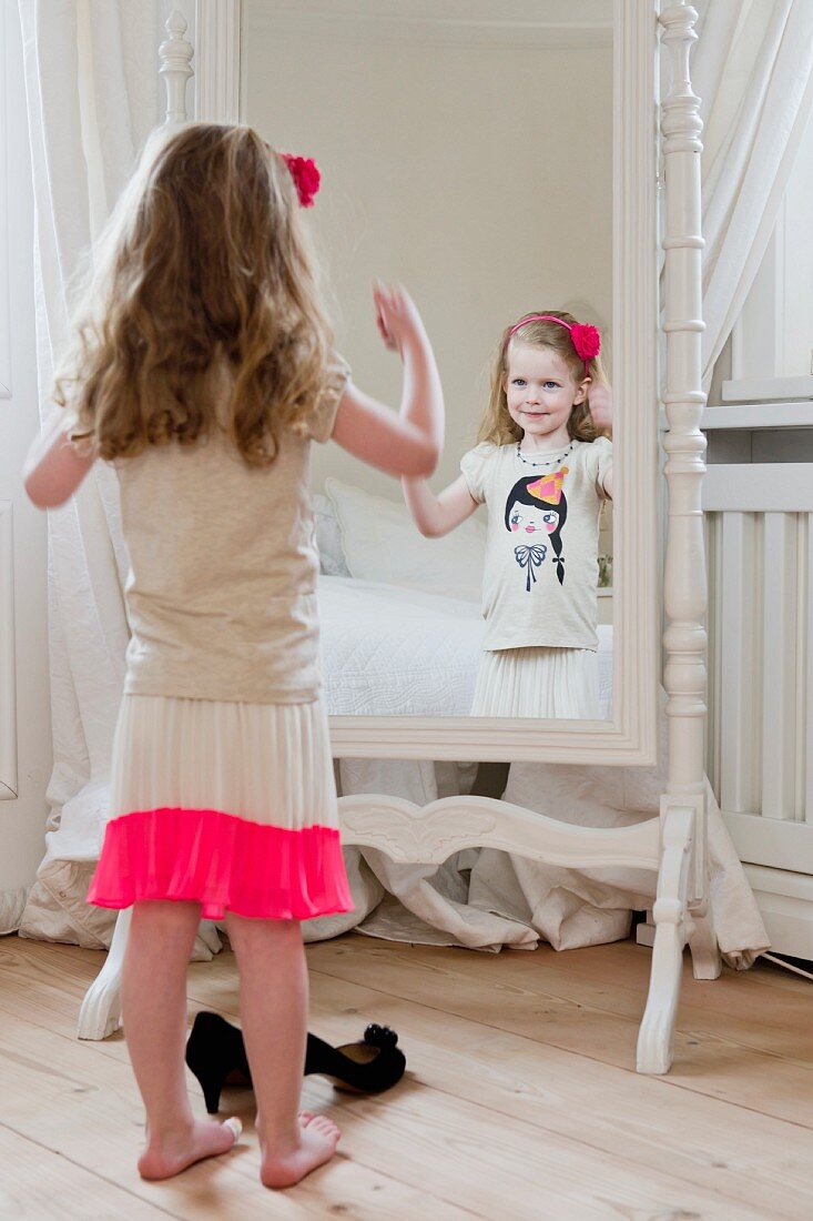 Kleines Mädchen posiert vor dem Spiegel