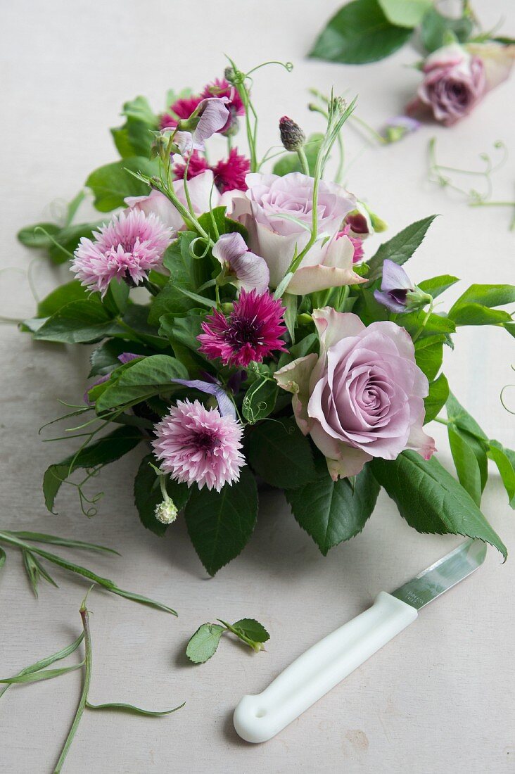 Tischgesteck aus Rosen, Kornblumen und Wicken