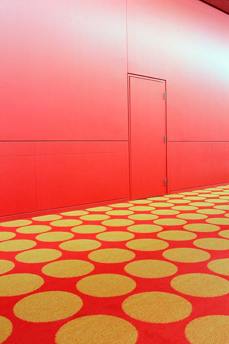 Roter Teppich mit gelben Punkten vor roter Wand