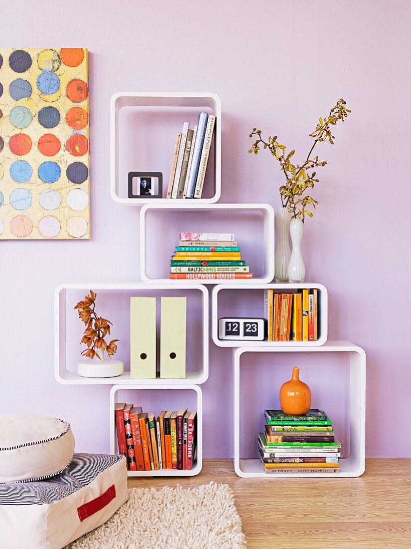 Modern shelving modules with rounded corners on wooden floor against lilac wall