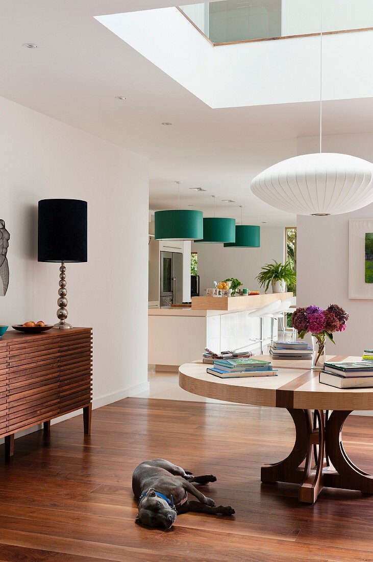 Offener Wohnraum mit Pendelleuchte im Japanstil, eleganter Tischlampe und grünen Hängeleuchten über Küchentheke