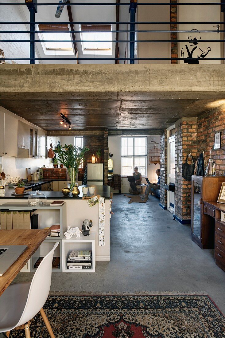 Loft-style interior with open-plan kitchen below mezzanine in roof space