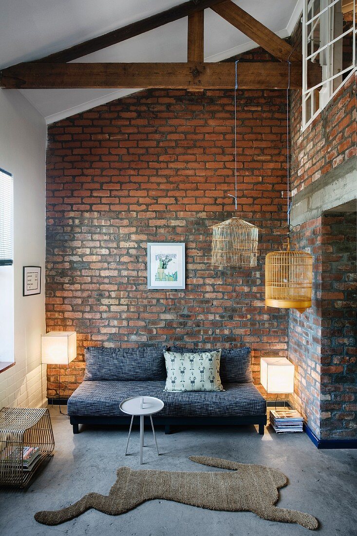 Moderne Loungeecke und Teppichvorleger mit Hasenmotiv in offenem, rustikalem Wohnraum mit Ziegelwand
