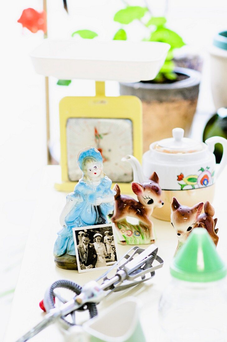 Flohmarktartikel - Kitschige Porzellanfiguren neben Vintage Schneebesen und diversen Retro Deko-Objekten auf dem Tisch